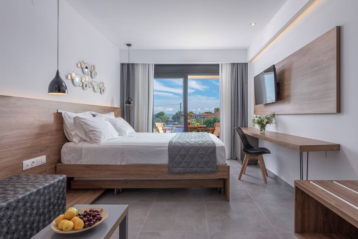 A modern hotel room with a bed, desk, and balcony view.