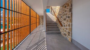 A modern interior with a wooden slatted wall, a stone wall staircase, and a tiled floor. - Dandelion Suites (Nikiti)