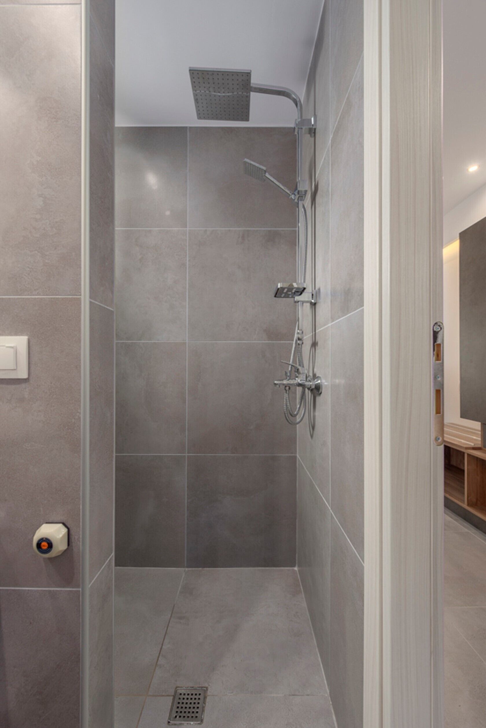 A modern shower with a handheld showerhead, a wall-mounted faucet, and a showerhead.