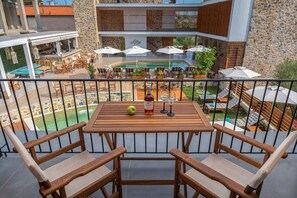Un balcon avec une table en bois, deux chaises, une bouteille de vin et un verre.