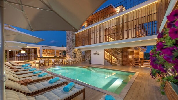 A poolside area with lounge chairs and a bar. - Dandelion Suites (Nikiti)