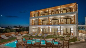 A modern two-story building with a pool area, outdoor seating, and a view of the sea. - Dandelion Suites (Nikiti)