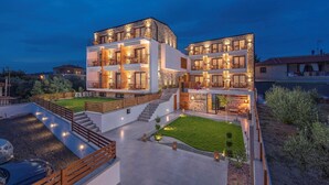 A modern two-story building with a reception area, outdoor seating, and a well-maintained garden. - Dandelion Suites (Nikiti)