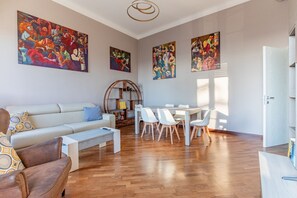 Una sala de estar moderna con sofá, mesa de comedor, sillas y obras de arte en las paredes.