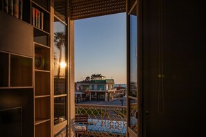 Un balcón abierto con vistas a edificios y una palmera.