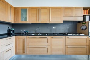 Una cocina moderna con armarios de madera, un lavamanos de acero inoxidable y una estufa a gas.