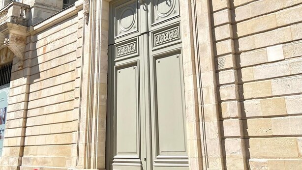 Un edificio con un'imponente porta doppia decorata e una facciata in pietra.