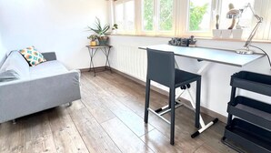 Una cucina moderna con pavimento in legno, un'area pranzo con un divano grigio, una sedia nera e un piano di lavoro bianco.