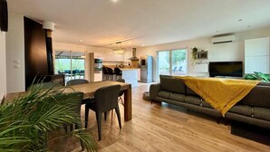A modern living room with a wooden dining table, a sofa, and a TV.