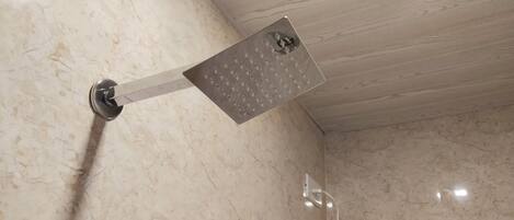A showerhead with a perforated cover, mounted on a wall with a marble finish.