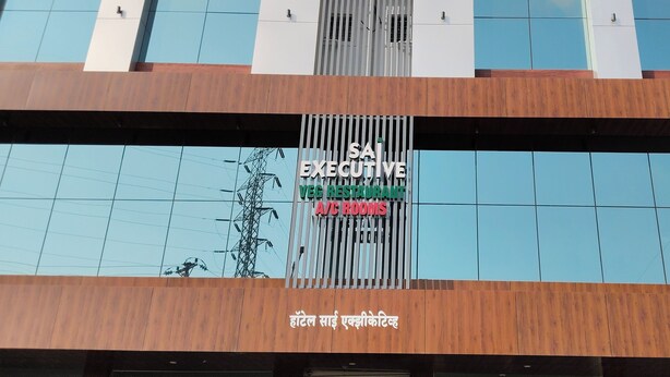 A modern building with a sign for "SAI EXECUTIVE VEC RESTAURANT A/C ROOMS". - Hotel Sai Executive (Rajgurunagar)