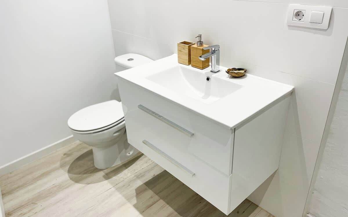A modern bathroom with a white sink, vanity, and toilet.