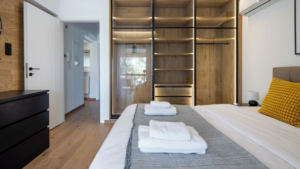 Un dormitorio moderno con una cama grande, un armario de madera y una mesita de noche.