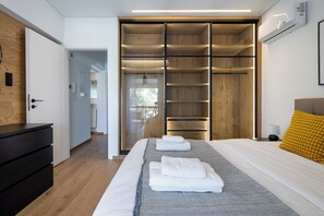 Een moderne slaapkamer met een groot bed, een houten garderobe en een nachtkastje.