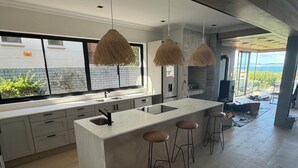 A modern kitchen with a large island, bar stools, and hanging pendant lights.