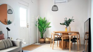 A modern living room with a sofa, a dining table with chairs, a potted plant, and a hanging light fixture. - Tinto Townhouse  (Seville)