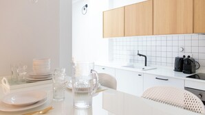 A modern kitchen with white cabinets, a tiled backsplash, and a white countertop. - Tinto Townhouse  (Seville)