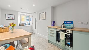 A modern kitchen with a light green countertop, a stainless steel oven, and a sign that reads "CHOP SHOP".