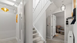 A clean, modern hallway with a carpeted staircase, a white door, and a ceiling light fixture.