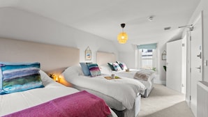 A bedroom with two beds, a ceiling light, and a view of the hallway.