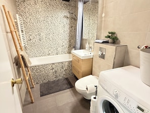 Un bagno con doccia, toilette, lavandino e lavatrice.