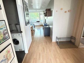 A laundry room with a washing machine, a drying rack, and a small table with a chair.
