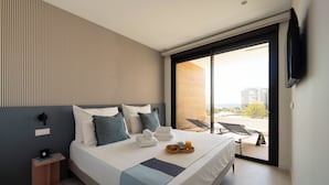 A modern hotel room with a large bed, a flat-screen TV mounted on the wall, and a balcony with a view of the city. - Lucentina Line (Villajoyosa)