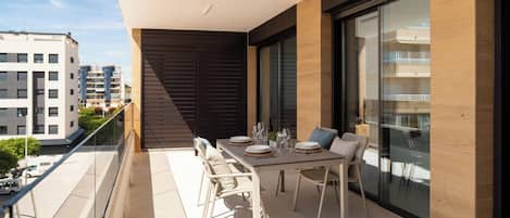 En balkon med et spisebord til fire personer, omgivet af fletstole.