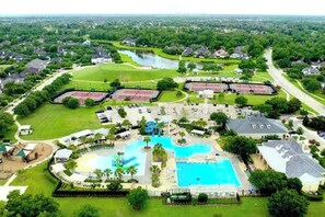 Un gran resort con múltiples piscinas, un campo de golf y un lago.