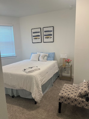 A bedroom with a bed, pillows, a bedside table with a lamp, and a chair. - The Clement Chateau - Brand New Home (Missouri City)
