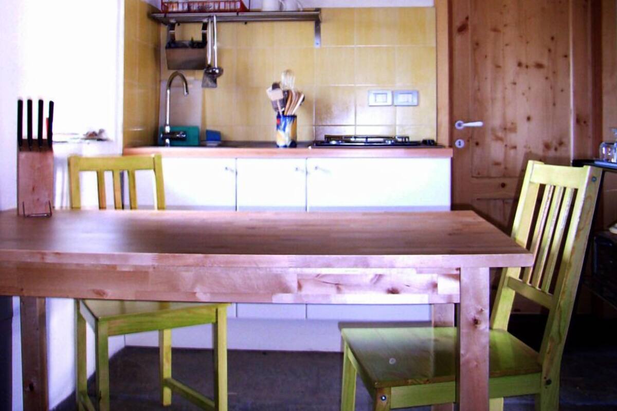 A kitchen with a wooden table and chairs, a stove, and a sink.