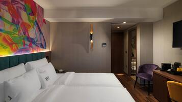 Habitación de hotel con una cama grande, un escritorio, una silla y un cuadro abstracto de colores en la pared.