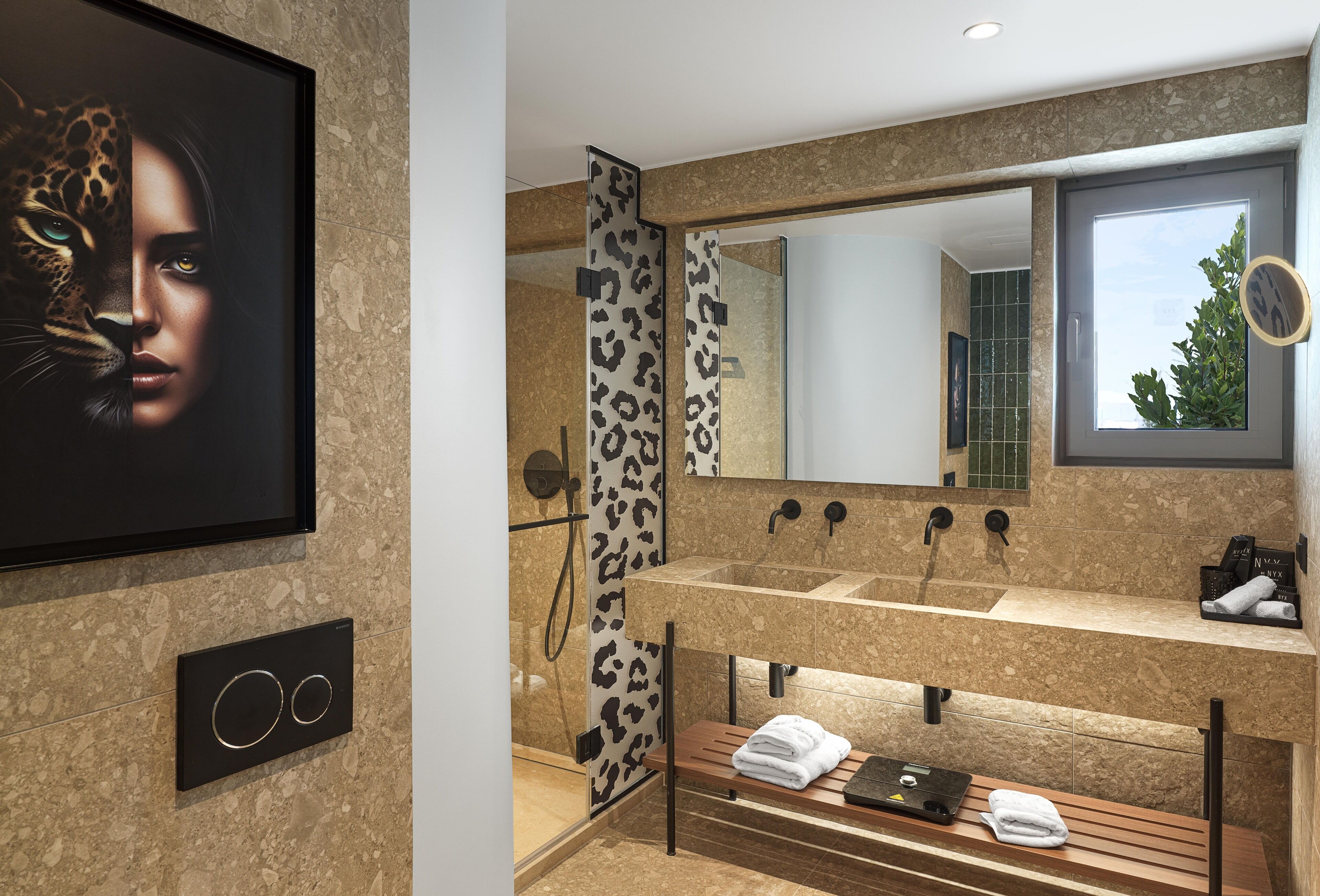 Un baño moderno con un espejo grande, una ducha con puerta de estampado de leopardo y un tocador con un banco.