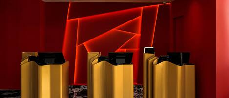 A reception area with three gold-colored counters and a red geometric wall design.