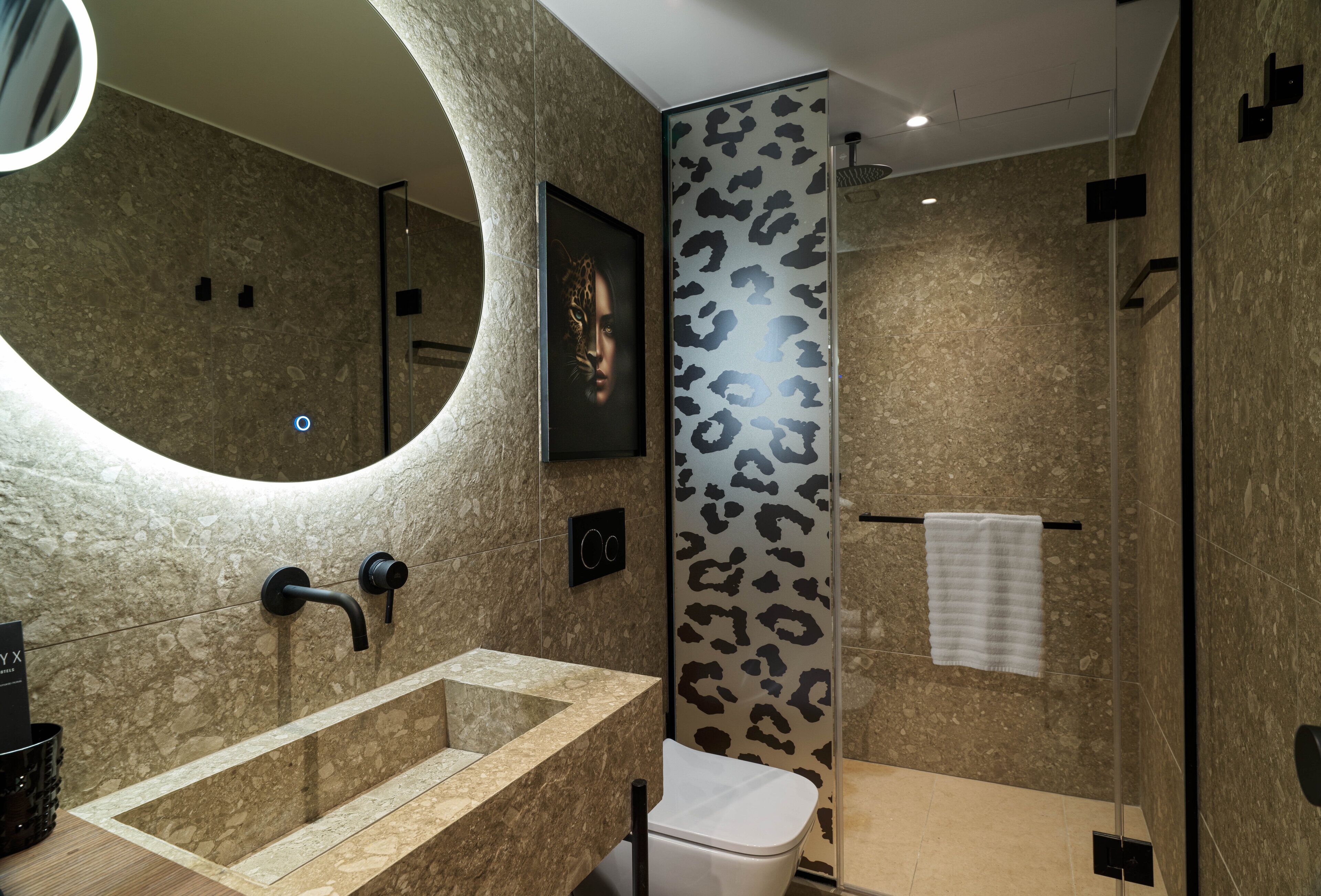 A modern bathroom with a curved sink, a toilet, and a shower area.