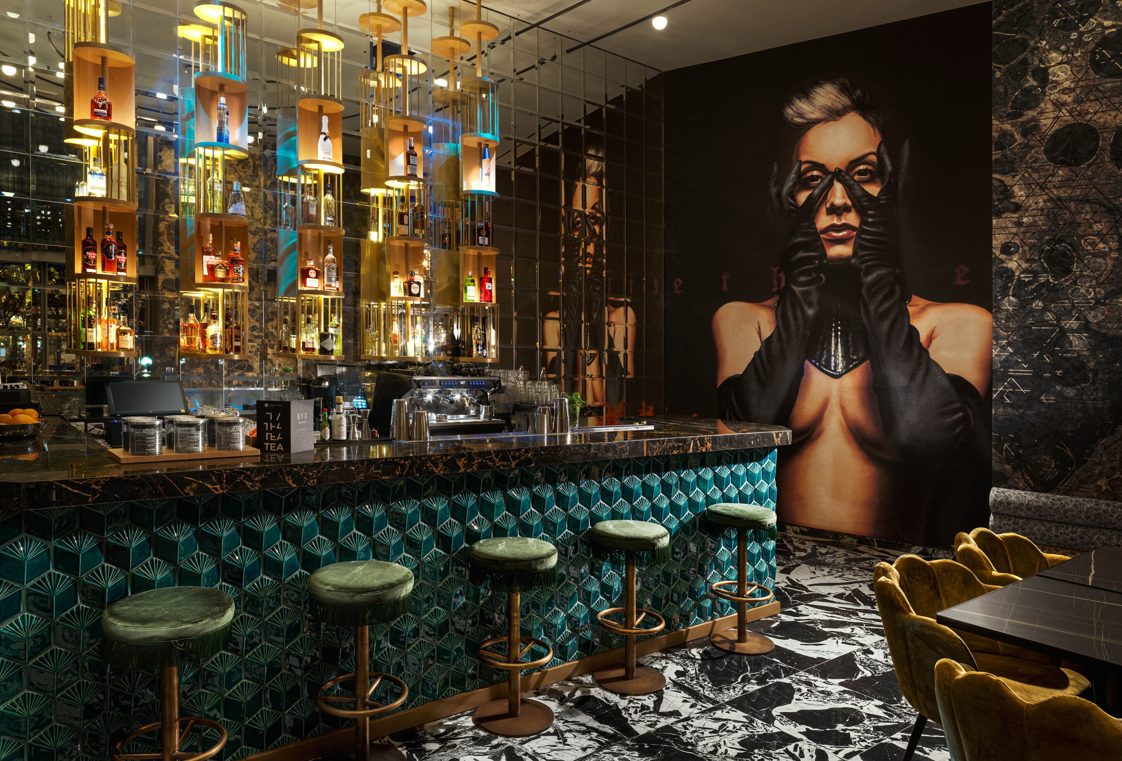 A bar area with a patterned tile floor, green bar stools, and a large mural on the wall.
