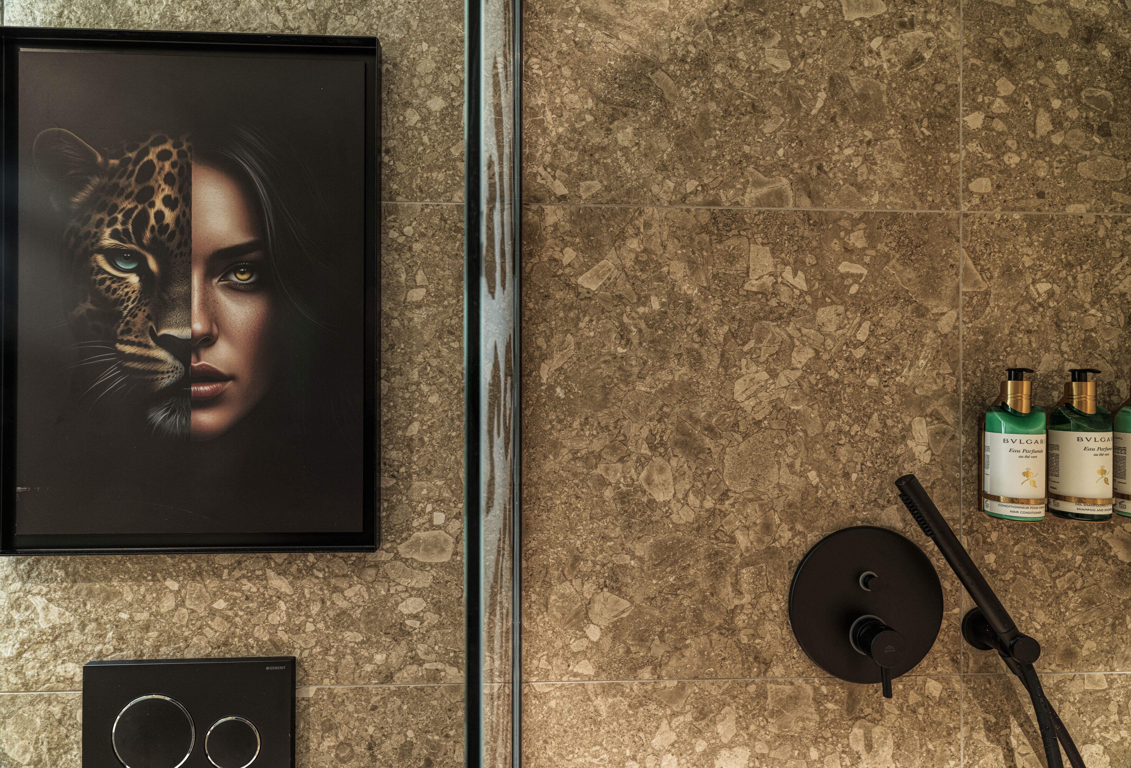Baño con una obra de arte enmarcada, artículos de aseo y cabezal de ducha.