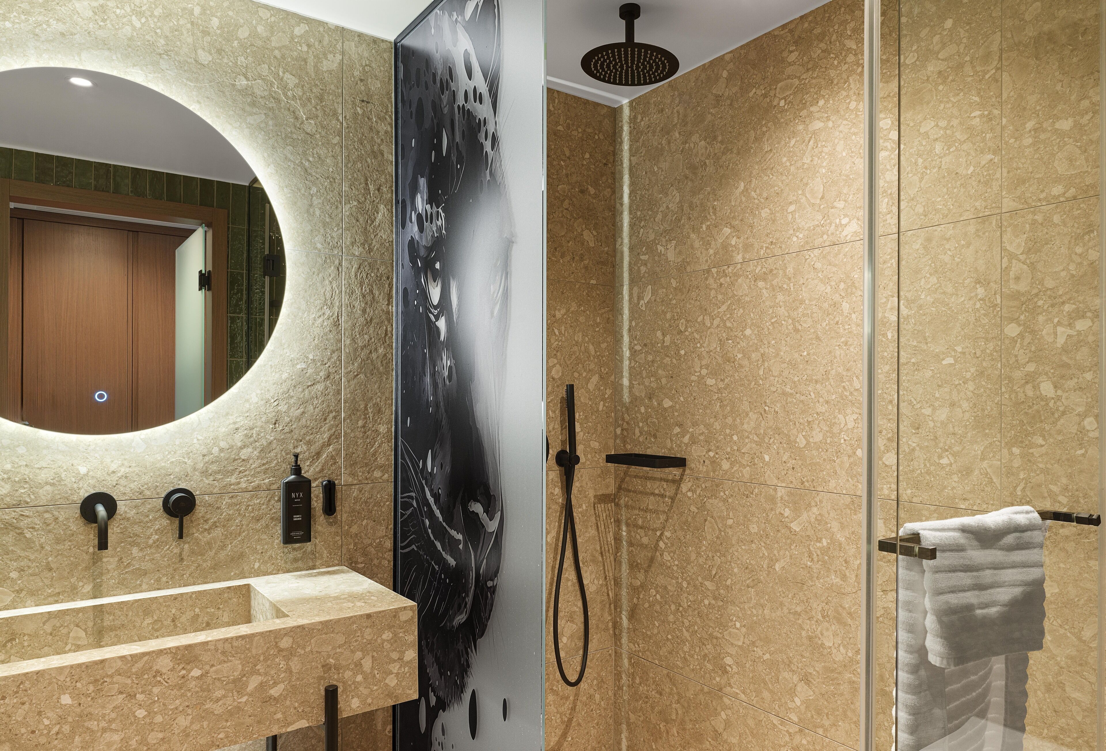 Une salle de bain moderne avec un grand miroir, une douche et un porte-serviettes.