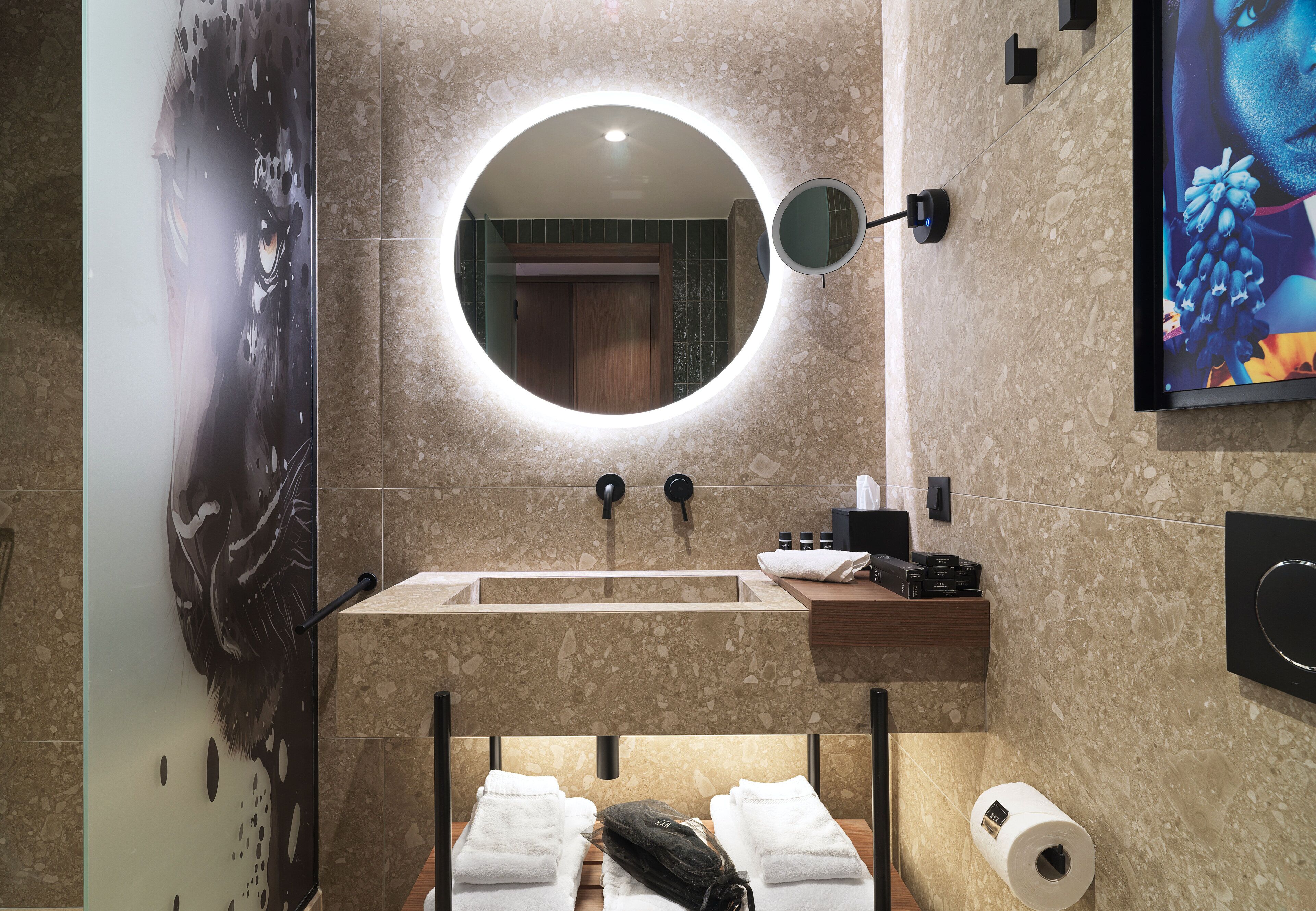 Une salle de bain moderne avec un miroir rond, un lavabo et un porte-serviettes.