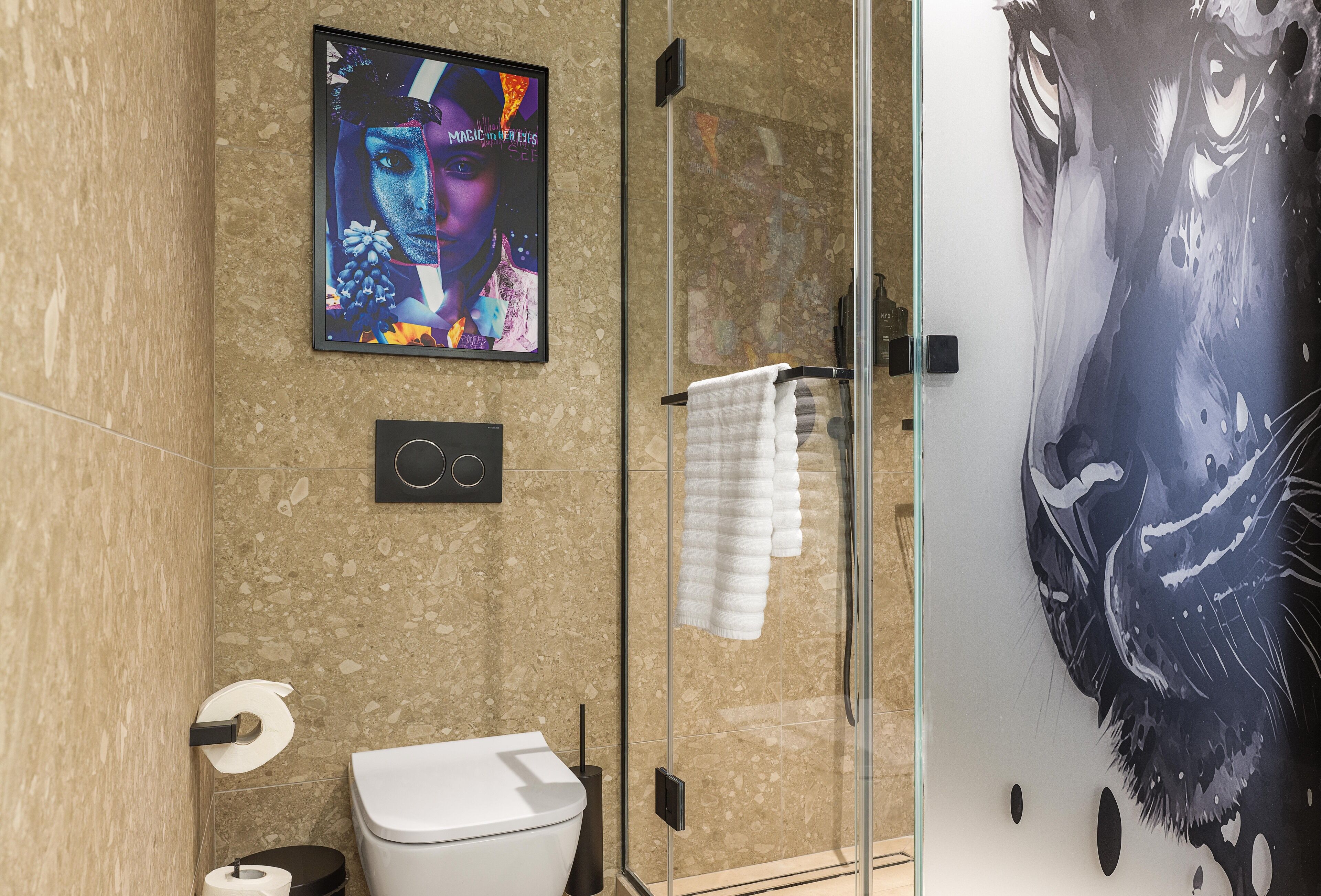 Een moderne badkamer met een glazen douchecabine, toilet en een televisie waarop een kleurrijk beeld wordt weergegeven.