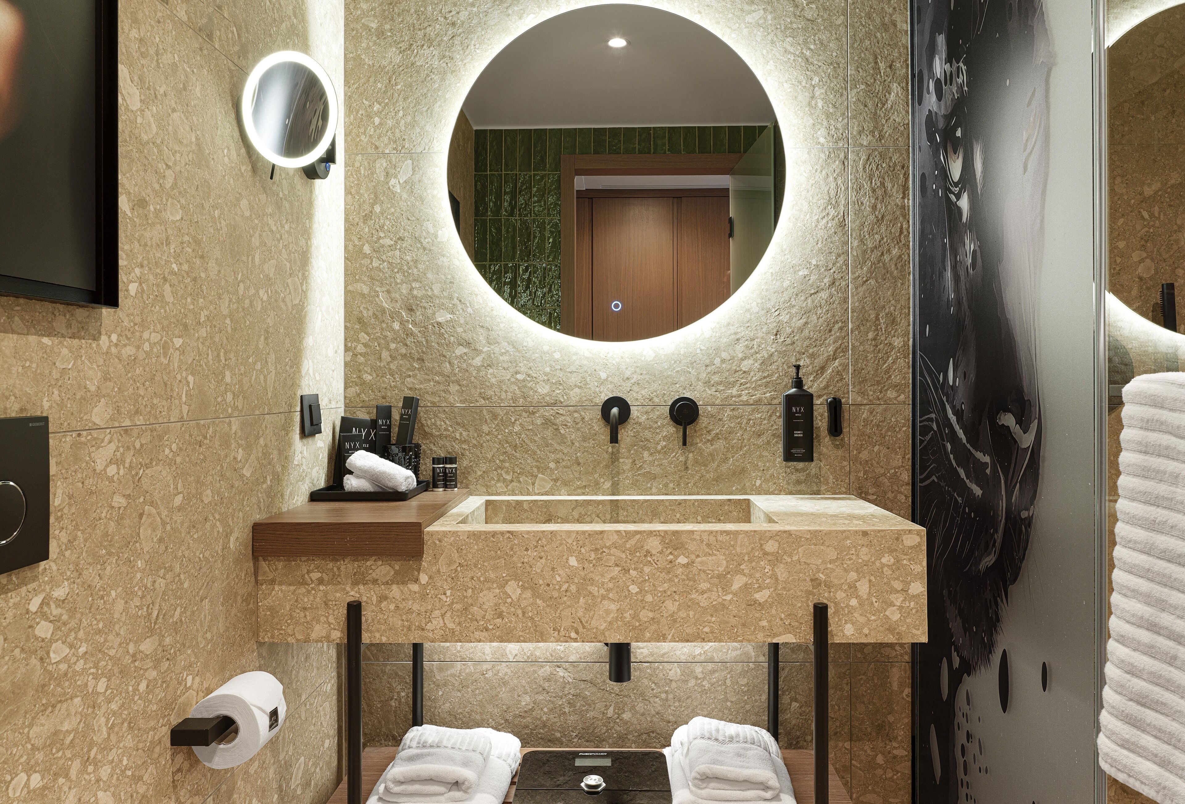 A bathroom with a large mirror, two sinks, a towel rack, and a toilet.