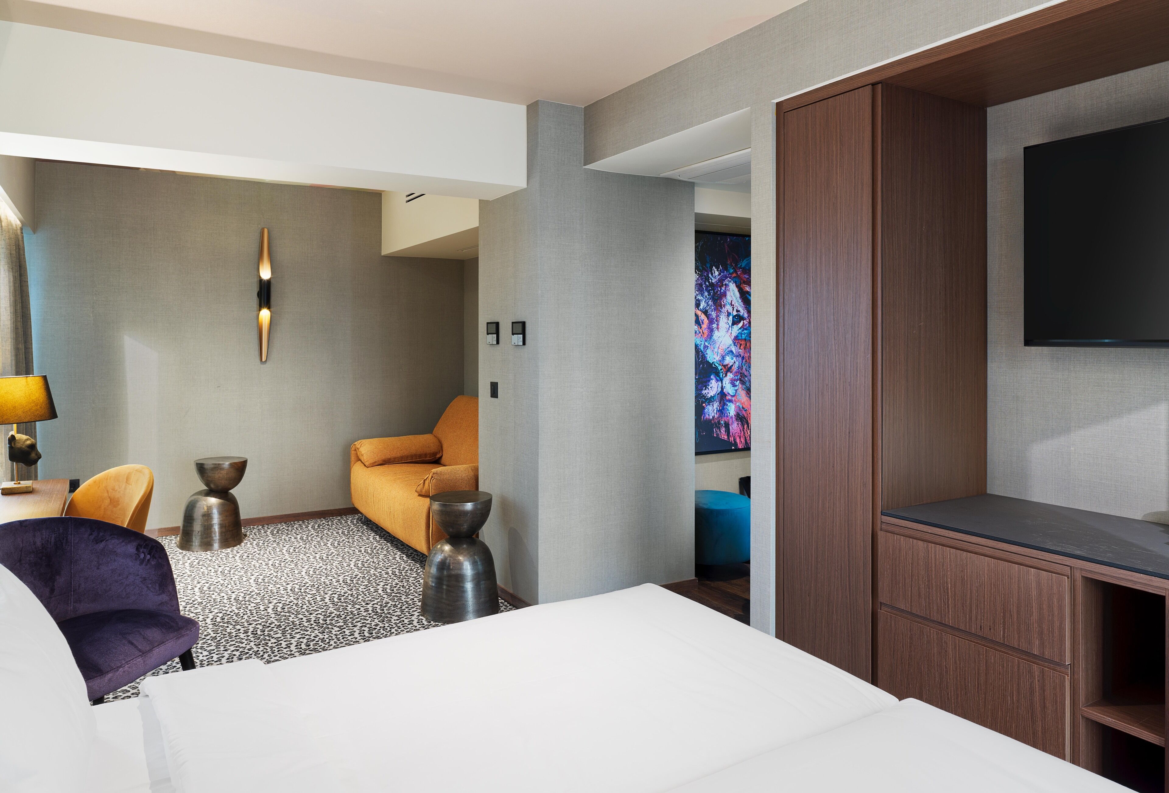 Une chambre d’hôtel moderne équipée d’un lit, d’un canapé, d’une télévision et d’une grande fenêtre.
