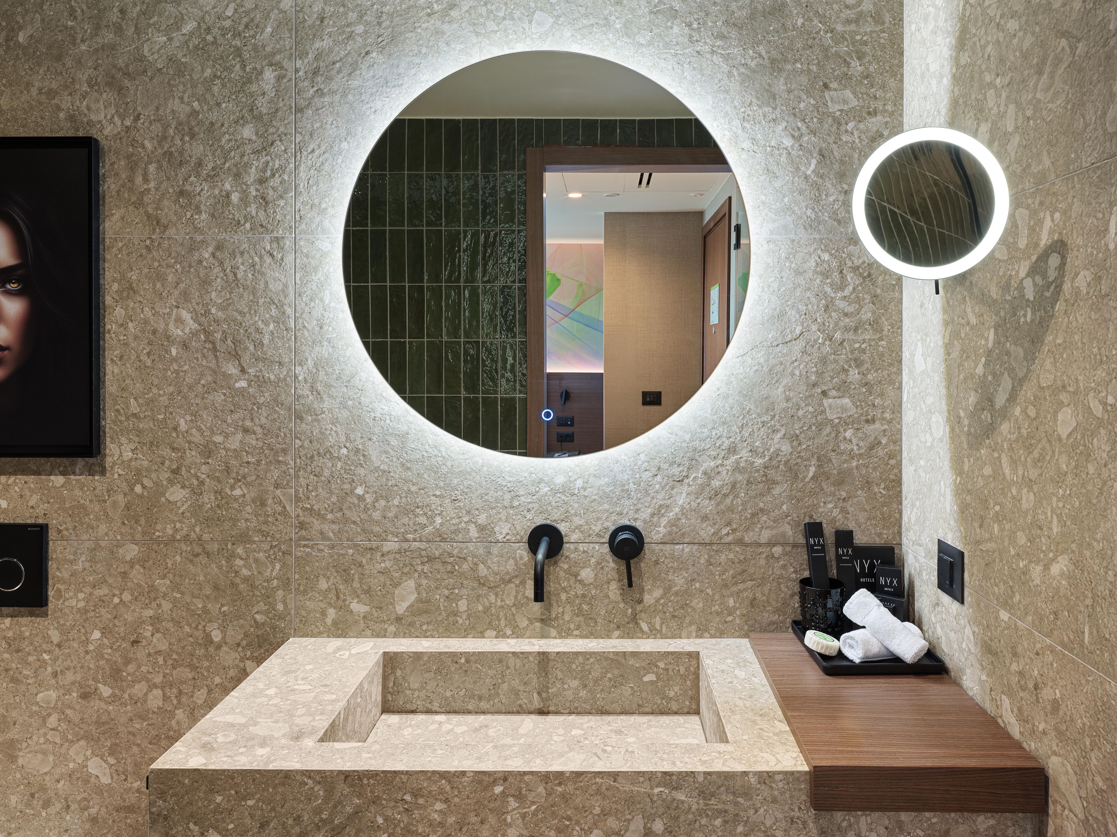 Une salle de bain avec un miroir rond, un lavabo et un porte-serviettes.