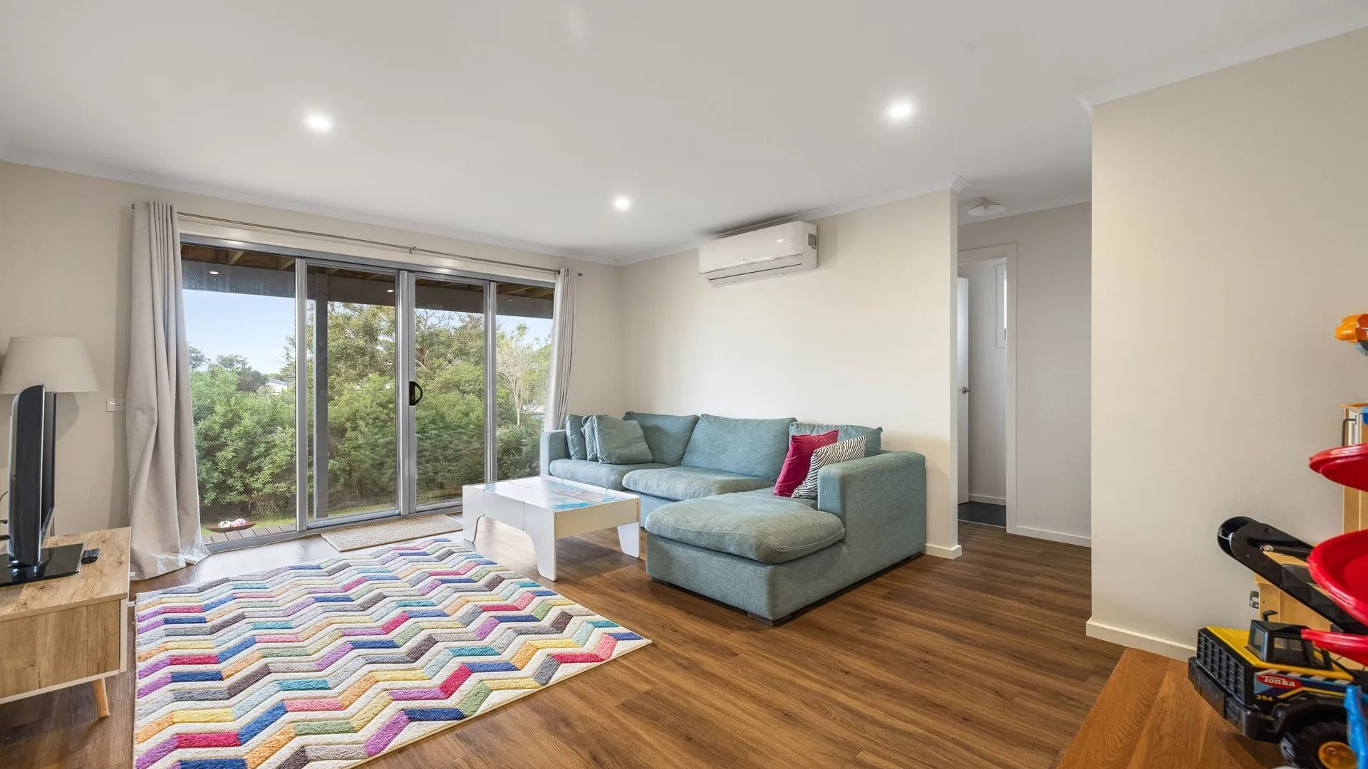 A modern living room with a sofa, a coffee table, and a colorful rug.