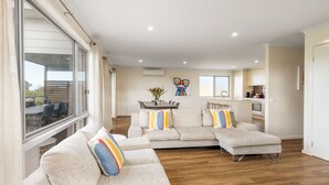 Una sala moderna con un sofá modular, un comedor y una cocina.
