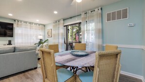 A dining area with wicker chairs and a round table, a sofa, and a ceiling fan. - 21 Forest Gardens: Walk to Beach, 2 Beds, Hosts 6. Free Bikes (Hilton Head Island)