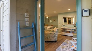 A room with a wooden floor, a floral sofa, a small table, and a mirror on the wall. - 21 Forest Gardens: Walk to Beach, 2 Beds, Hosts 6. Free Bikes (Hilton Head Island)