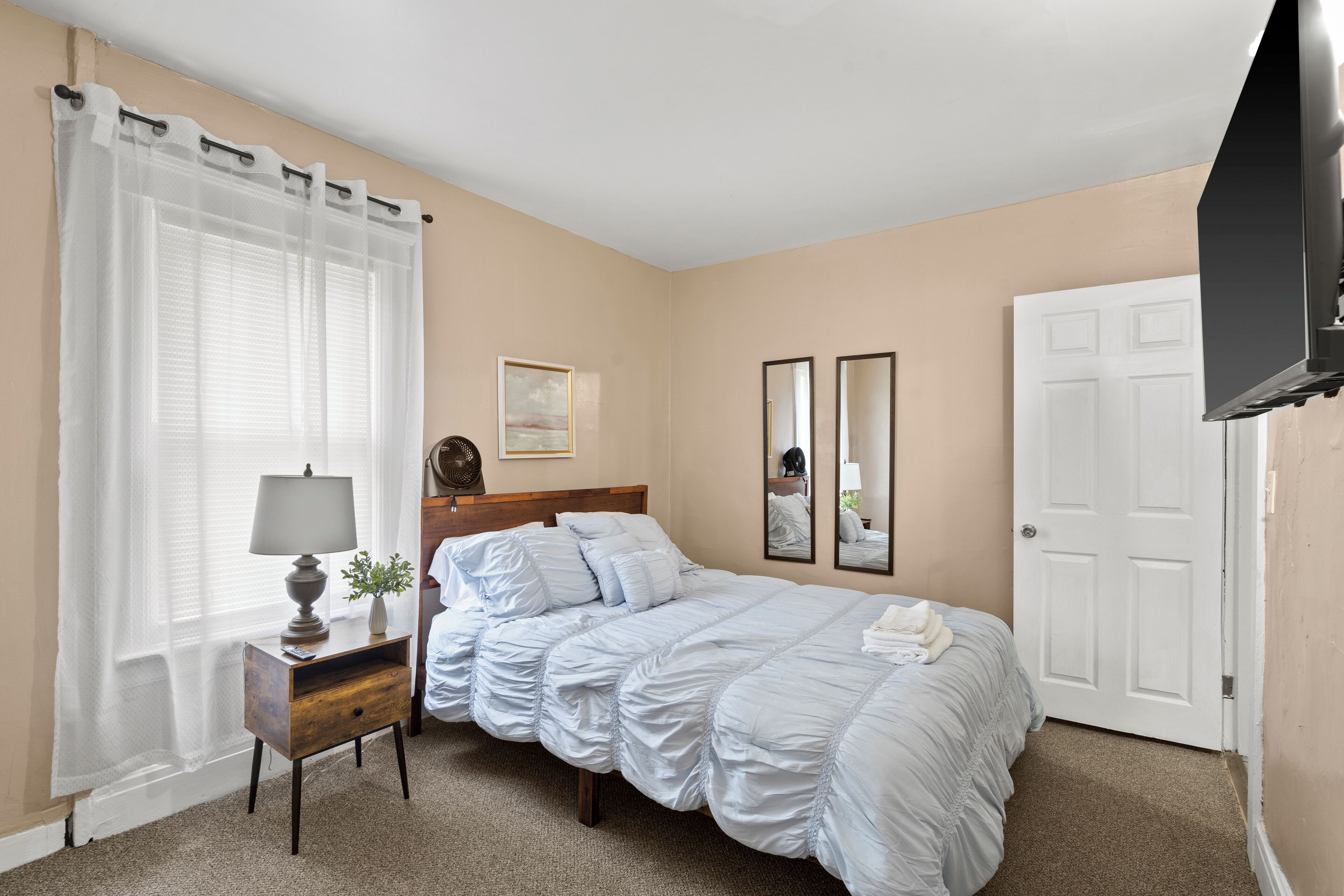 Une chambre à coucher avec un lit, une table de chevet, une lampe et une porte.
