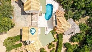 An aerial view of a property with a swimming pool, multiple buildings with tiled roofs, and landscaped gardens.