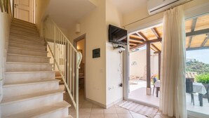 A staircase leading to a balcony with a TV mounted on the wall and a view of the outdoors.